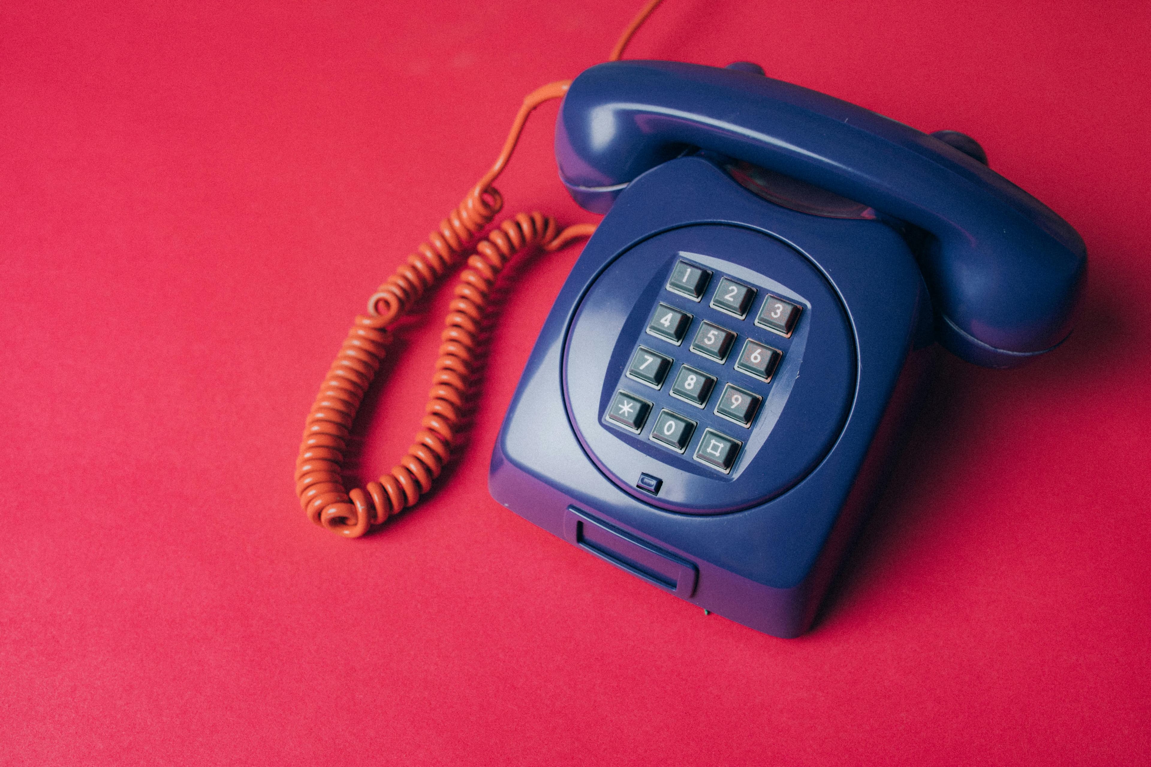 Blue telephone on a pink background for contact support